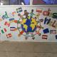 Wandbild mit Weltkugel, darum viele Kinder und Nationalflaggen