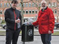 Die Grünen-Politiker Marc Muckelberg und Peter Goetzke vor einem Mülleimer
