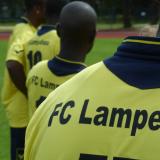 Vier Spieler des FC Lampedusa, gelbe Trikots mit schwarzem Aufdruck von hinten.